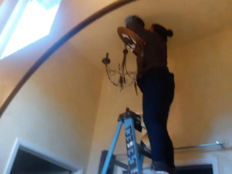 Electrician installing a chandelier in a Aurora residence